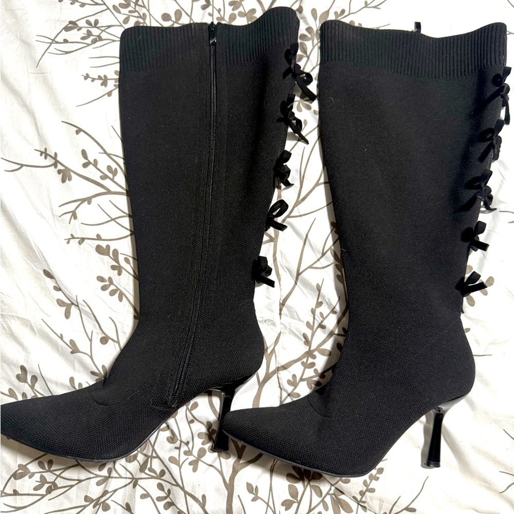 Black, knee high heeled boot with zipper and bows on back
